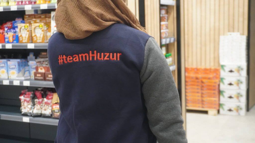 Blick in den Huzur-Markt in Stolberg: Teammitglied mit #teamHuzur-Weste zwischen den Regalen